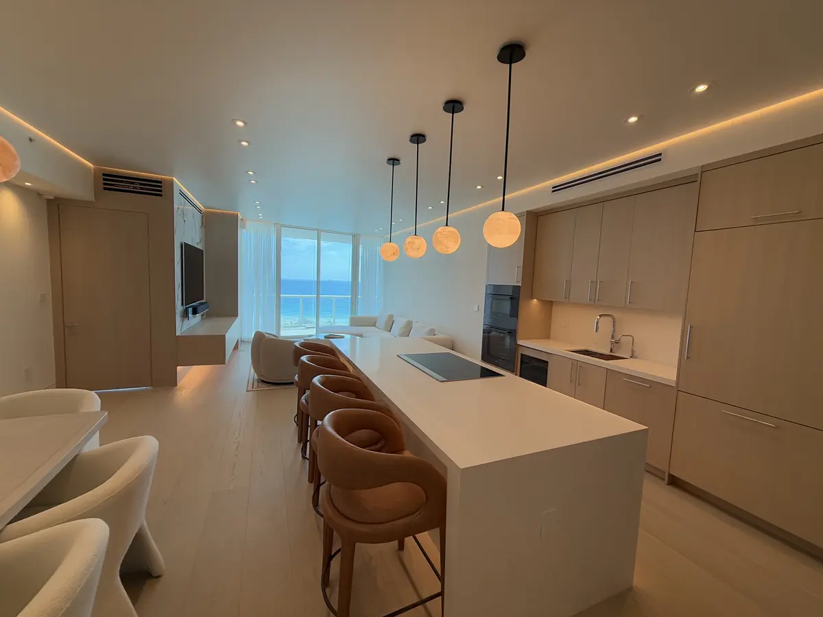 Renovación de cocina terminada en Continuum South Tower, Miami Beach: isla tipo cascada, lámparas colgantes de alabastro y gabinetes de madera