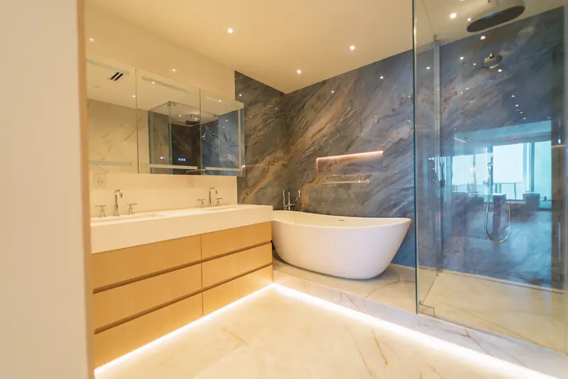 Remodelación de condominio en Miami Beach: baño principal en Continuum South Tower con pared de mármol azul, bañera independiente y mueble de lavabo flotante