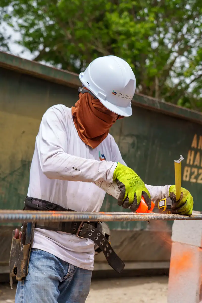 Miembro del equipo de Ballagas Construction midiendo y cortando varillas de refuerzo en Kaēlo Residence, Miami Shores